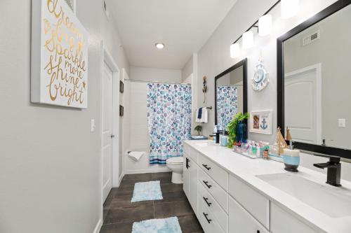 a white bathroom with two sinks and a toilet at Relaxstay - Private Spacious 1br Apartment near Galleria Dallas in Dallas