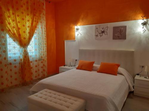 ein Schlafzimmer mit einem Bett mit orangefarbenen Wänden und einem Fenster in der Unterkunft Appartamento Giardino in Domus de Maria