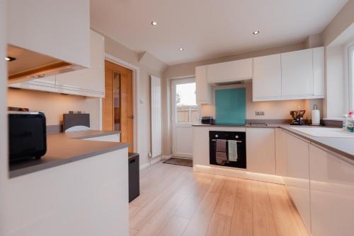 a kitchen with white cabinets and a wooden floor at Luxury Recently Renovated 3 Bedroom home in Sandwich Kent in Sandwich