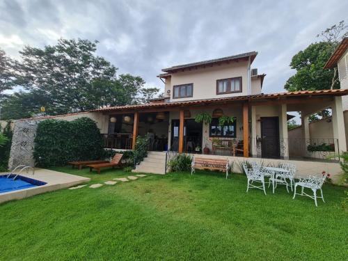 una casa con un patio con sillas y una piscina en Casa Bonita - Aconchegante para se divertir e descansar, en Pirenópolis