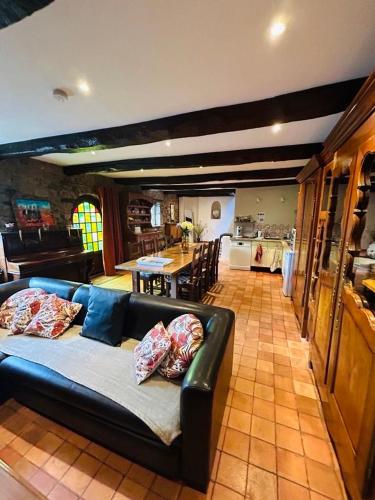 un salon avec un canapé et une cuisine dans l'établissement Maison traditionnelle bretonne proche de la mer, à Quemper-Guézennec