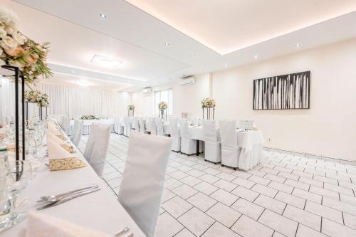 une salle de banquet avec des tables blanches et des chaises blanches dans l'établissement Hotel Zlaté Košice, à Košice