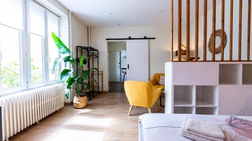 a living room with a bed and a yellow chair at Le Nid - hébergement cosy in Dijon