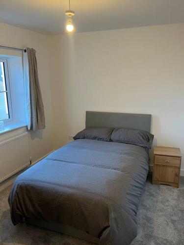 ein Schlafzimmer mit einem Bett mit einer blauen Decke und einem Fenster in der Unterkunft House in Dorset in Iford