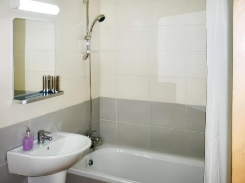 a white bathroom with a sink and a bath tub at 2 bedrooms apartement with shared pool furnished terrace and wifi at Larnaca 2 km away from the beach in Tersephanou