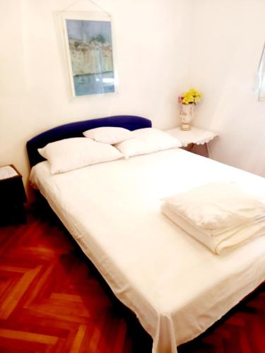 a bed with white sheets and pillows in a room at Apartman SunnySide in Rogoznica