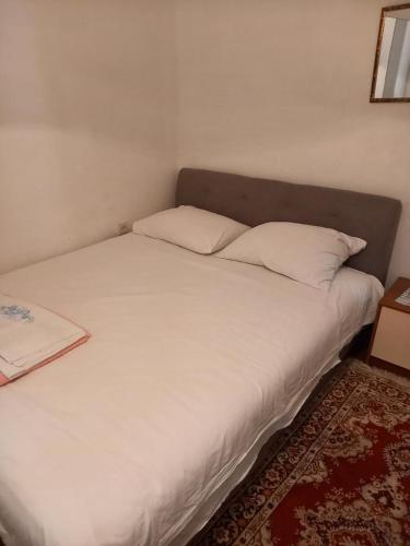 a bed with white sheets and pillows in a room at Apartman SunnySide in Rogoznica