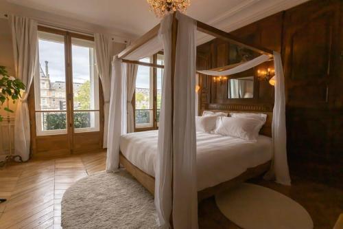 - une chambre avec un lit à baldaquin et une grande fenêtre dans l'établissement Apt vue Louvre et Seine, à Paris