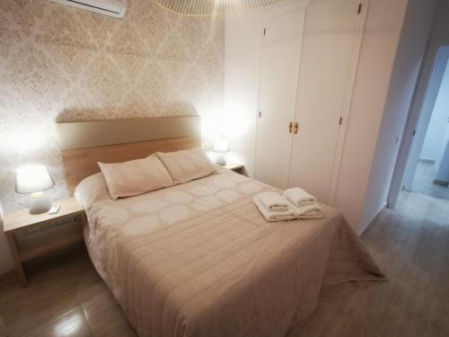 ein Schlafzimmer mit einem Bett mit zwei Handtüchern darauf in der Unterkunft Słoneczny Apartament Parque IV in La Mata