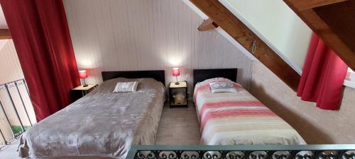 2 bedden in een zolderkamer met rode gordijnen bij Combe Belle in Vézac