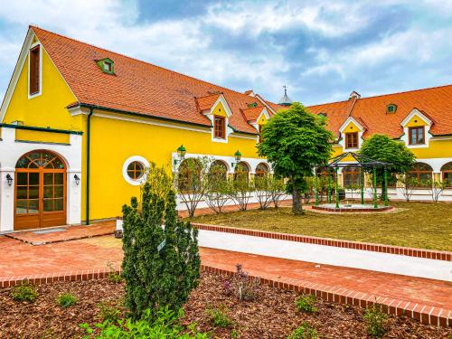 a yellow and white building with a yard at Hotel Römerstein in Loipersdorf bei Fürstenfeld