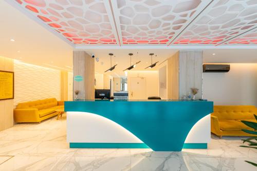 a lobby with a blue counter and yellow chairs at Hotel Nova in Mar del Plata