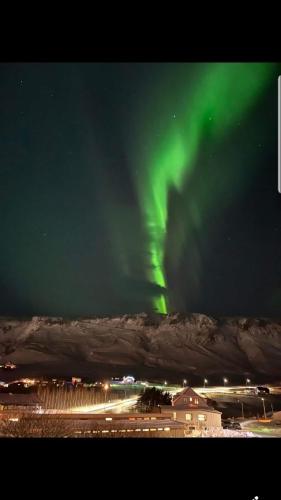 an aurora in the sky over a city with a building at Vík Hostel in Vík