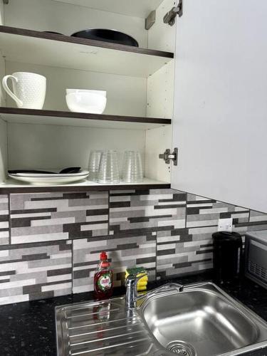 - un comptoir de cuisine avec évier, assiettes et vaisselle dans l'établissement 1 bedroom kitchen Flat, à Nottingham