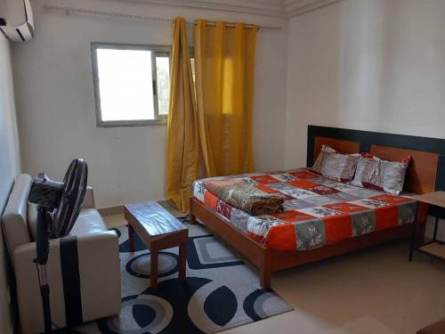 1 dormitorio con 1 cama, 1 silla y 1 ventana en fleur, en Dakar