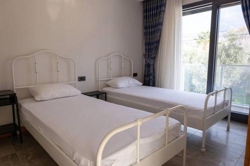 two beds in a room with a window at Çeşmede sakin lüks havuzlu villa in Çeşme