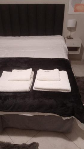a bed with black blanket and white towels on it at Asturias in Presidencia Roque Sáenz Peña