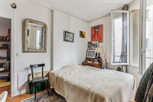 une chambre avec un lit, un miroir et une chaise dans l'établissement Boulogne proche Roland Garros - 2 chambres, à Boulogne-Billancourt