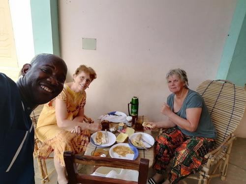un grupo de personas sentadas alrededor de una mesa con comida en CHEZ ALFA, en Jugu