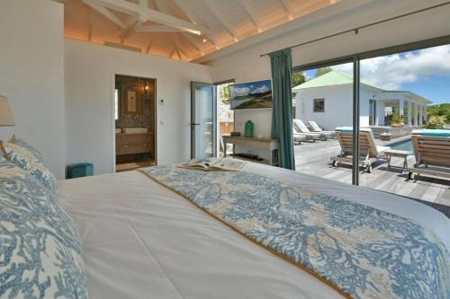 Schlafzimmer mit einem Bett und Blick auf eine Terrasse in der Unterkunft Villa Vogue 5 Bedroom Villa in Saint Barthelemy