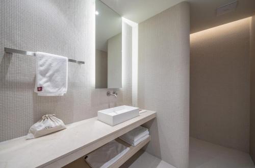 a white bathroom with a sink and a mirror at 대구 수성 더 아르코 호텔 라이온즈파크점 