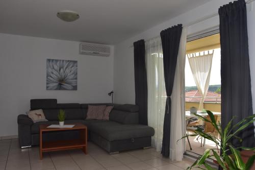 uma sala de estar com um sofá e uma janela em Apartmani Andrea em Čižići
