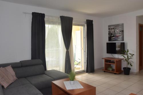 ein Wohnzimmer mit einem Sofa und einem Fenster in der Unterkunft Apartmani Andrea in Čižići
