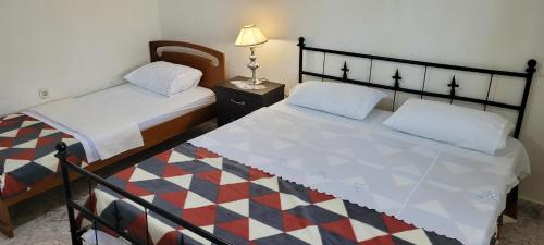 ein Schlafzimmer mit 2 Betten und einem Tisch mit einer Lampe in der Unterkunft Guesthouse Reçka in Gjirokastër