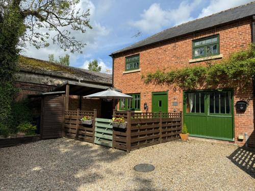 a brick building with a fence and an umbrella at Piper Cottage, Bilbrough, York in Bilbrough