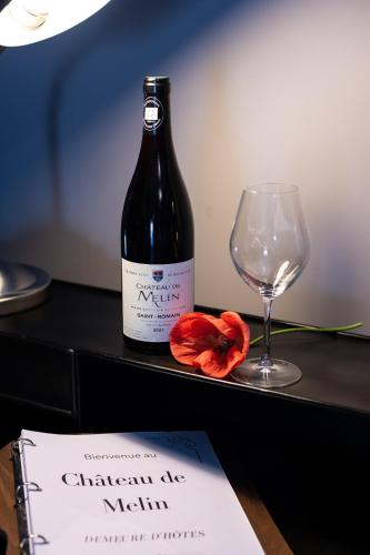 a bottle of wine sitting next to a glass at Château de Melin - B&B in Auxey-Duresses