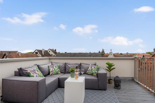 a patio with a couch on a balcony at NAMASTÉ Homes - Ferienwohnung mit Dachterrasse in Bad Windsheim
