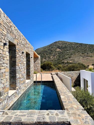 a stone house with a swimming pool and a mountain at Egeo Paros in Kampos Paros