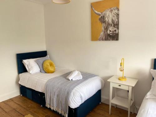 a bedroom with a bed and a cow picture on the wall at Number 6 Crossgate in Fife