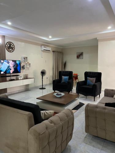 a living room with a couch and chairs and a tv at Well furnished and very spacious apartment in Wuye in Abuja