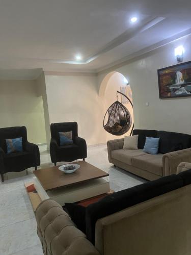a living room with couches and a table and chairs at Well furnished and very spacious apartment in Wuye in Abuja