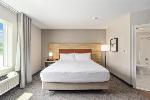 a bedroom with a large bed and a bathroom at Candlewood Suites - Ocala I-75 by IHG in Ocala
