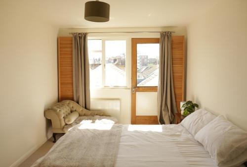 1 dormitorio con 1 cama, 1 silla y 1 ventana en Sunny Seaside Sanctuary - Two Bedroom Apartment en Brighton & Hove