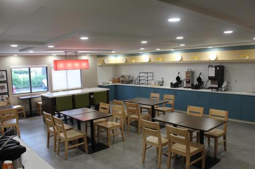 a restaurant with tables and chairs and a kitchen at Country Inn & Suites by Radisson, Dunbar - Charleston in Dunbar