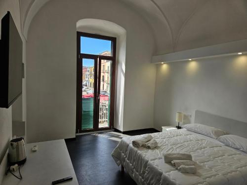 a bedroom with a large bed and a large window at La Dama del Castello in Bosa