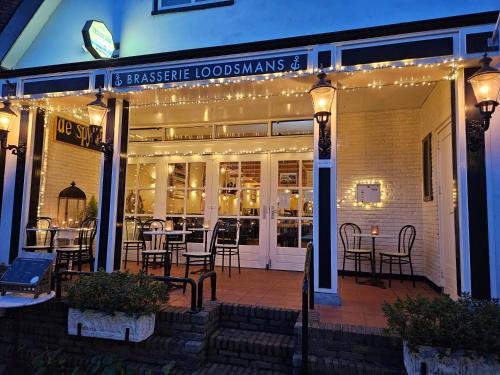 a restaurant with tables and chairs on a patio at Hotel-Restaurant Loodsmans Welvaren in Den Hoorn