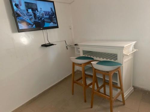 a table and two stools with a tv on a wall at Studio meublé sur la vdn liberté 6 extension in Dakar