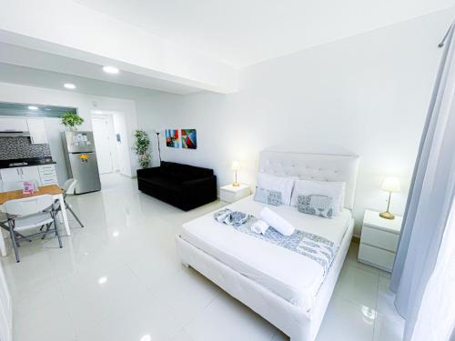 um quarto branco com uma cama e uma cozinha em DELUXE SUITES STUDIOS DUCASSI Sol Caribe HOTEL Bavaro WIFI Parking BBQ Beach CLUB & SPA em Punta Cana