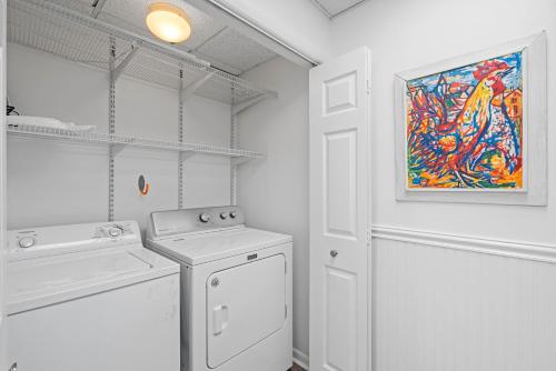 a white laundry room with a washing machine and a painting at High Pointe Resort 131 in Inlet Beach