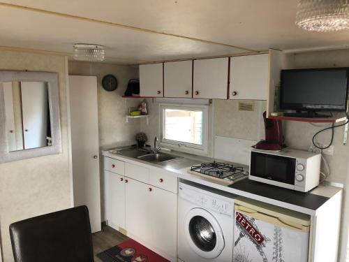 uma pequena cozinha com fogão e micro-ondas em Mobilhome à Fréjus à 15 minute de la mer sur terrain indépendant em Fréjus