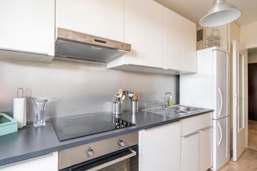 une cuisine avec des armoires blanches et un évier dans l'établissement Le Saint Aloïse - Balcon, Vue à 10min du Centre, à Strasbourg