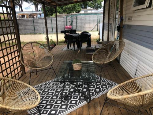 a porch with three chairs and a table with a piano at Mobilhome à Fréjus à 15 minute de la mer sur terrain indépendant in Fréjus