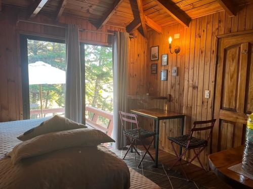 Un dormitorio con una cama y un escritorio y una ventana. en Cabañas Hostal Punta de Lobos Surf & Relax, en Pichilemu