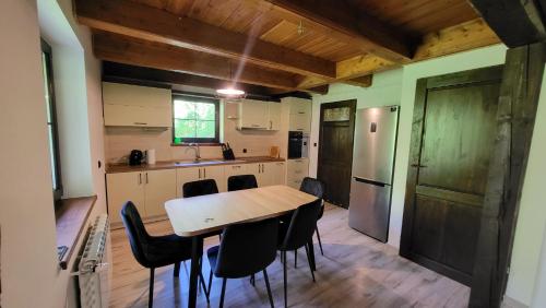 uma cozinha com uma mesa de madeira e cadeiras pretas em Domek Zacisze em Graboszyce