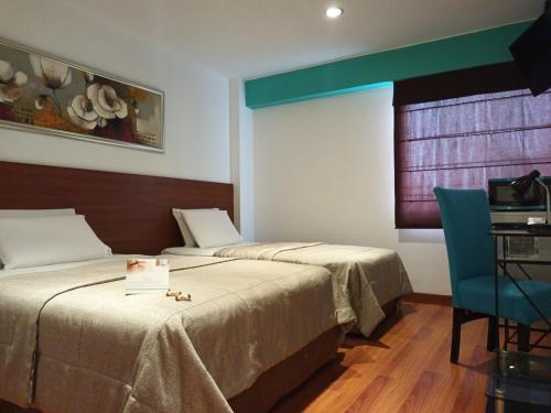 una camera con due letti, un tavolo e una sedia di Hotel Vila Santa a Lima