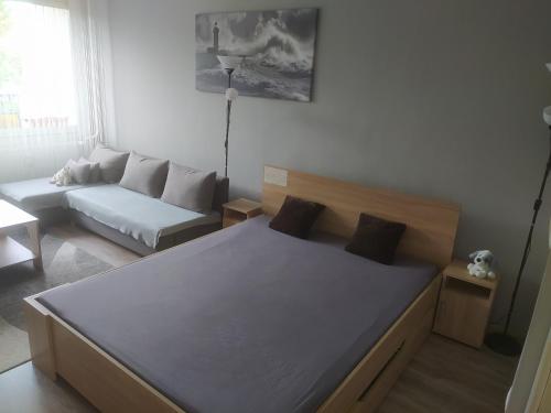 a bedroom with a large bed and a couch at Krénusz Vendégház 2. in Kaposvár